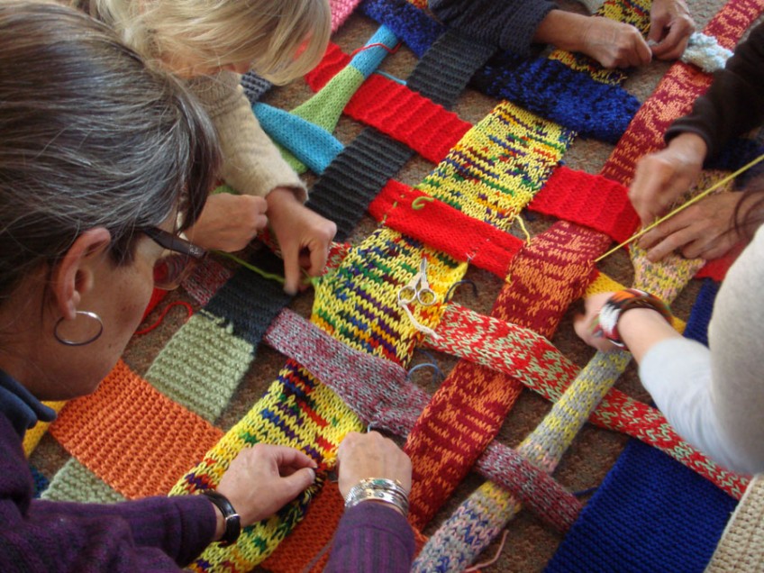 people weaving knitted strips